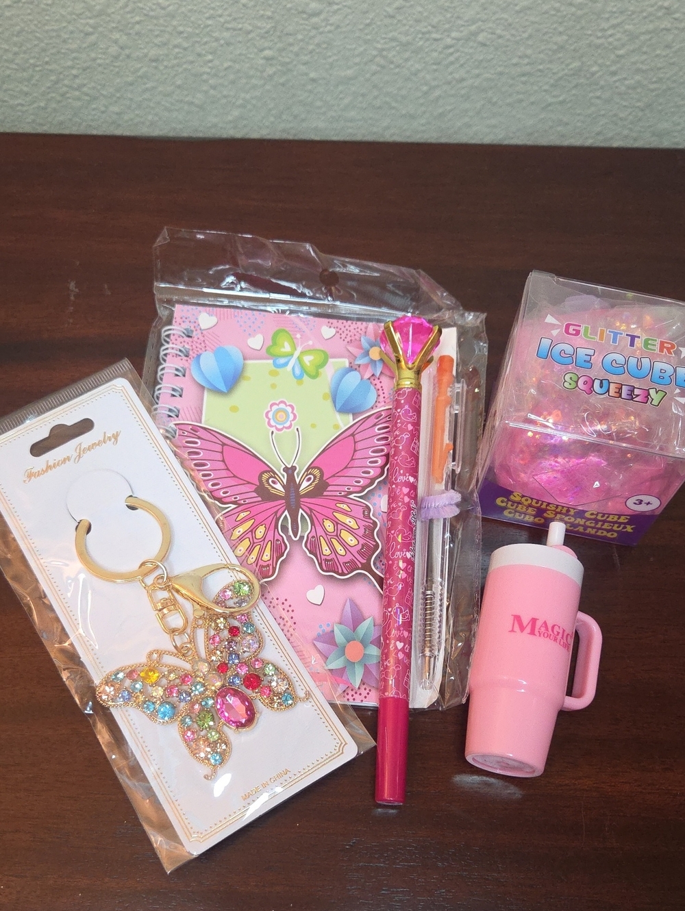 Pink Butterfly Bag Charm, Notebook, Glitter Squeezy Cube, Pen and Lip Balm.